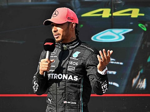 Pole position winner Mercedes' British driver Lewis Hamilton gives an interview as he stands in front of a screen showing his car with number 44.
