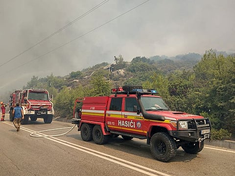 Firetrucks line up as firefighters try to extinguish a wildfire burning near Alaerma, Rhodes Island, Greece, July 22, 2023. 