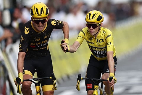 Jumbo-Visma's Danish rider Jonas Vingegaard wearing the overall leader's yellow jersey (right) celebrates his overall victory with Jumbo-Visma's Belgian rider Tiesj Benoot as he cycles to the finish line after the 21st and final stage of the 110th edition of the Tour de France cycling race on Sunday.