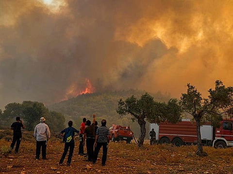 People stand in front of a forest fire in New Peramos, near Athens, on July 19, 2023. [File image]