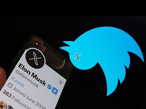 This illustration shows the Twitter bird logo upside down in the background of Elon Musk’s screen advertising an "X" as a replacement logo, in Los Angeles. 