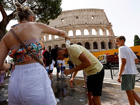 A woman pours water on a man near the Colosseum during a heatwave across Italy.