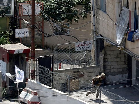 A Lebanese soldier takes cover at the entrance of the Ain Al Hilweh Palestinian refugee camp, Lebanon's largest Palestinian refugee camp, during clashes between Fatah movement and militants in the camp in the southern coastal city of Sidon on July 30, 2023.  