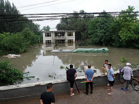 People look at a partially submerged building in a flooded area, after heavy rains in Fangshan district in Beijing
