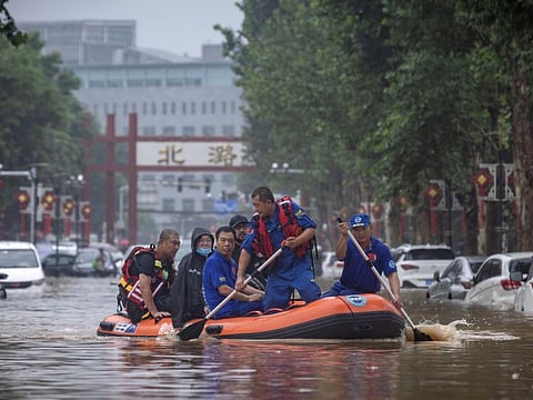 Rescue workers in a boat go through a flooded street in a neighbourhood where days of heavy rain from remnants of Typhoon Doksuri have caused heavy damage in Beijing on August 1, 2023.  