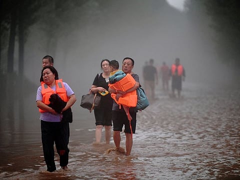 Residents wade through floodwaters following heavy rainfall in Zhuozhou, Hebei province, China.