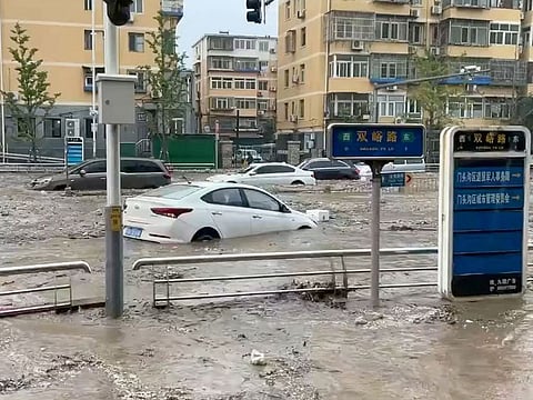 Cars are partially submerged as water gushes on a flooded street, after Typhoon Doksuri made landfall and brought heavy rainfall, at the Mentougou district, in Beijing.