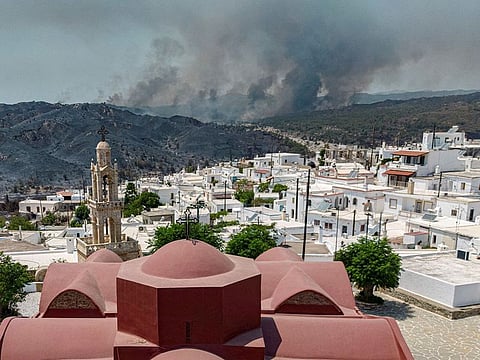 A view of the village of Asklipieio, as a wildfire burns in the background on the island of Rhodes, Greece.