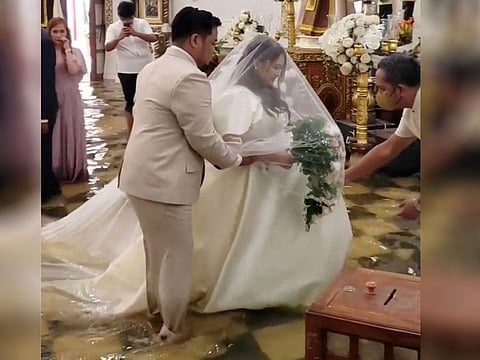 The bride walks down a flooded aisle in her wedding gown after Typhoon Doksuri floods a church in Malolos, Philippines.