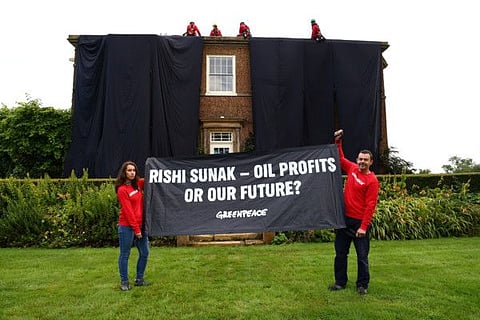 Greenpeace activists hold a banner while others cover British Prime Minister Rishi Sunak's £2m manor house in oil-black fabric in protest of his backing for a major expansion of North Sea oil and gas drilling amidst a summer of escalating climate impacts, in Yorkshire, Britain August 3, 2023.  