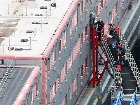 People carrying bags board the Bibby Stockholm barge at Portland Port.