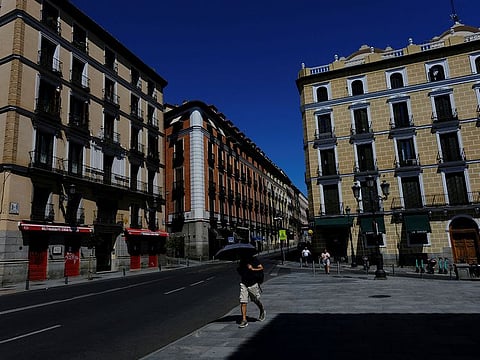 A man shelters from the sun underneath an umbrella on his way to work as Spain braces for the third heatwave of the summer in Madrid, Spain