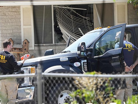 With a broken window in the background, FBI agents process the home of Craig Robertson who was shot and killed by the FBI in a raid on his home this morning on August 9, 2023 in Provo, Utah. 