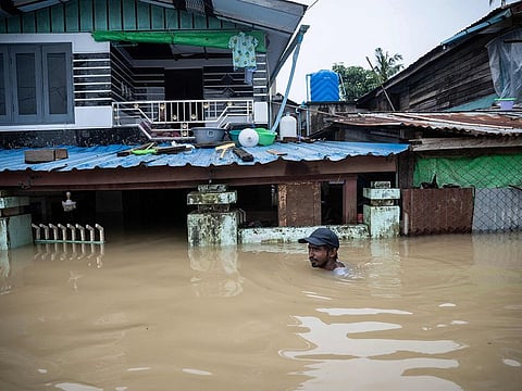 A man wades through a flooded street in Bago township in Myanmar's Bago region on August 12, 2023. 