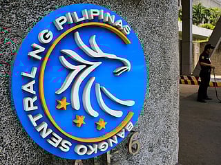 A security guard stands beside a logo of the Bangko Sentral ng Pilipinas (Central Bank of the Philippines) posted at the main gate in Manila, Philippines April 28, 2016.
