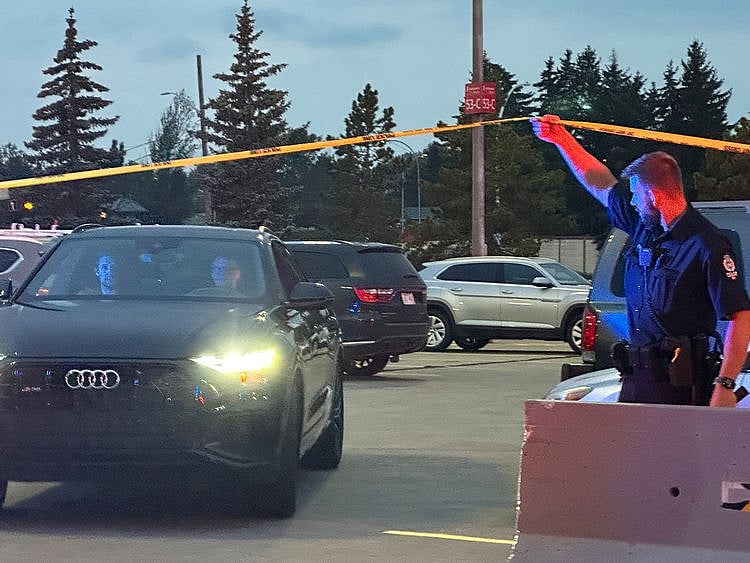 A police officer holds up crime scene tape to allow people to leave after a shooting incident at the West Edmonton Mall in Edmonton, Alberta