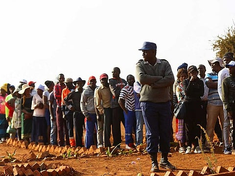 A police officer looks on as locals wait to cast their vote during the Zimbabwe general elections in Kwekwe, outside Harare, Zimbabwe August 23, 2023. 