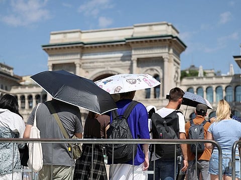 People use umbrellas to hide from the sun, as they queue to enter the Milan's Duomo Cathedral, during a heatwave, in Milan, Italy, August 21, 2023. 