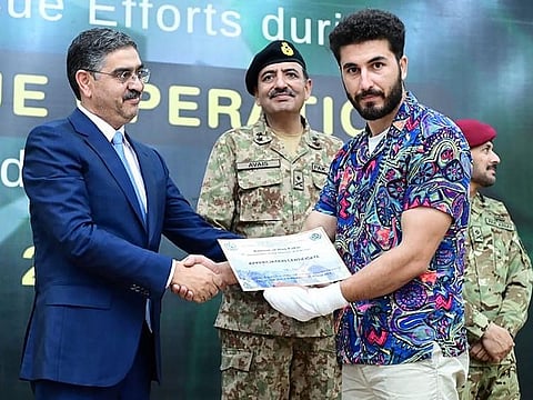 This handout photo taken and released by Pakistan's Press Information Department (PID) on August 24, 2023, shows Pakistani caretaker Prime Minister Anwaar-ul-Haq Kakar (L) presents a certificate to Muhammad Ali Swati, a zipline adventure company owner who was involved in rescuing 6 students in an rescue operation during a ceremony in the honor of rescuers efforts in cable car accident at the Prime Minister office in Islamabad. 