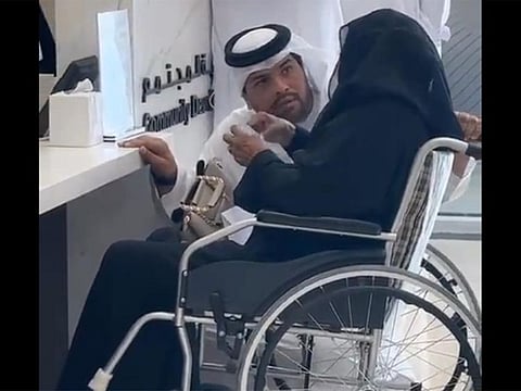  Screen grab of a video showing Jamal Abdulrahman, an Emirati official at the Community Development Authority in Dubai, kneeling down to serve an elderly woman in Dubai.