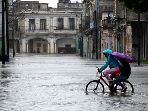 People ride a bicycle through a flooded street in Havana, on August 29, 2023, during the passage of tropical storm Idalia.  