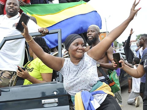 Residents gesture and hold a Gabon national flag as they celebrate in Libreville on August 30, 2023 after a group of Gabonese military officers appeared on television announcing they were "putting an end to the current regime" and scrapping official election results that had handed another term to veteran President Ali Bongo Ondimba.  