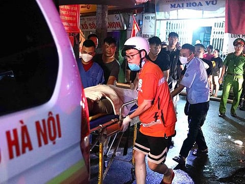 This picture taken and released by the Vietnam News Agency (VNA) on September 13, 2023 shows rescue workers carrying victims following a major fire at an apartment block in Hanoi. 