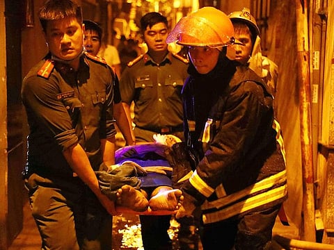 Rescue workers carrying victims following a major fire at an apartment block in Hanoi.