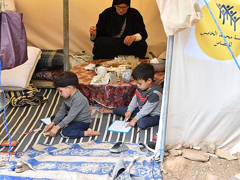 Children draw inside their tent at a camp for earthquake victims in Amizmiz on September 15, 2023.  
