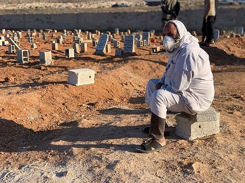 A man sits by the graves of the flash flood victims in Derna.