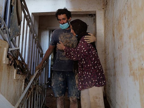 Ilham Al Debiani, who said she was preparing for her son's wedding when the deadly storm hit her city, is hugged by her son at her house in Derna.
