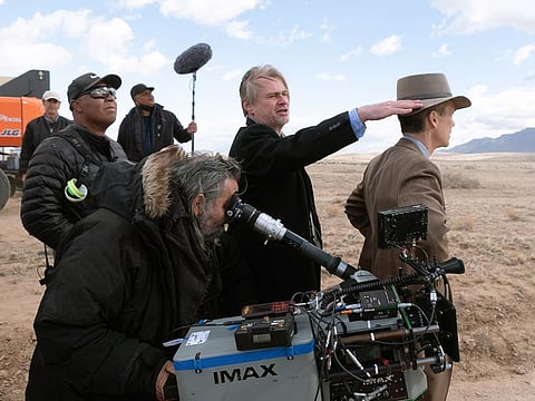 Director Christopher Nolan, center, and Cillian Murphy, right, on the set of "Oppenheimer." 