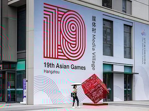 A woman walks past a logo of the 2022 Asian Games at the media village in Hangzhou, China's eastern Zhejiang province on September 21, 2023