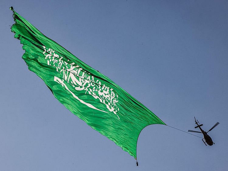 A helicopter flies over with a giant Saudi flag during an air show marking Saudi Arabia's 93rd National Day celebrations in Riyadh on September 23, 2023.  