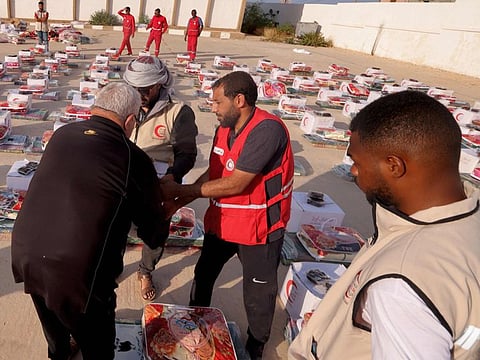 Members of the UAE Red Crescent distribute food aid to disaster survivors in Libya's eastern port city of Derna.