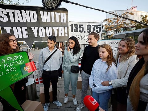 Young Portuguese citizens hold placards as they arrive at the European Court of Human Rights (ECHR) for a hearing in a climate change case involving themselves against 33 countries, in Strasbourg, eastern France, on September 27, 2023.  