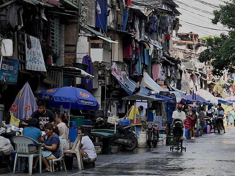 People walk past makeshift houses in Manila.