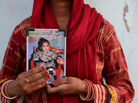 Poli Devi, whose 11-month-old daughter Janvi was among the children who died due to kidney injury after consuming contaminated cough syrup, holds a photo of her at their house in Ramnagar on the outskirts of Jammu, India, March 28, 2023.  
