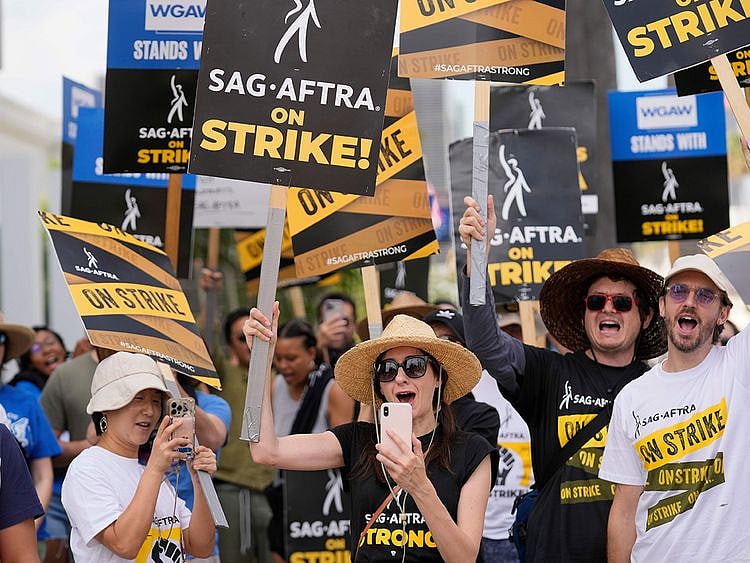 Picketers carry signs on the picket line outside Netflix on Wednesday, Sept. 27, 2023, in Los Angeles. Hollywood's writers strike was declared over Tuesday night when board members from their union approved a contract agreement with studios, bringing the industry at least partly back from a historic halt in production. The actors strike continues in their bid to get better pay and working conditions.