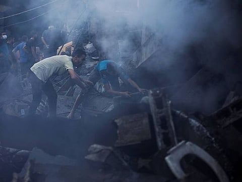 Palestinians search for casualties under the rubble in the aftermath of Israeli strikes, amid the ongoing conflict between Israel and the Palestinian Islamist group Hamas, in Khan Younis in the southern Gaza Strip, October 14, 2023
