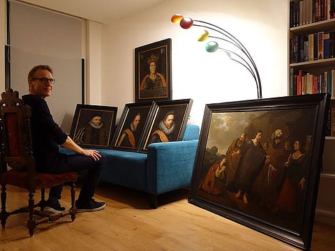 Dutch art detective Arthur Brand, dubbed the "Indiana Jones of the Art World", posing next to six paintings he has recovered, including a portrait of William of Orange and the first depiction of a seventh-century king.