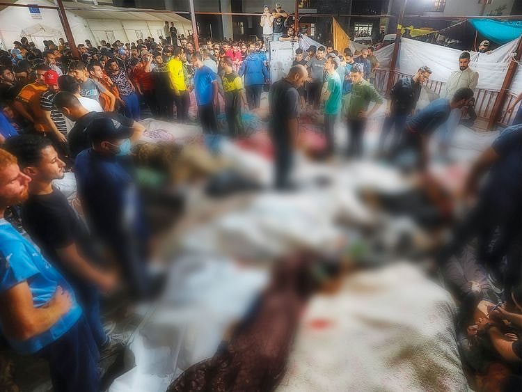 People gather around bodies of people killed in Israeli airstrikes on the Al Ahli Baptist Hospital