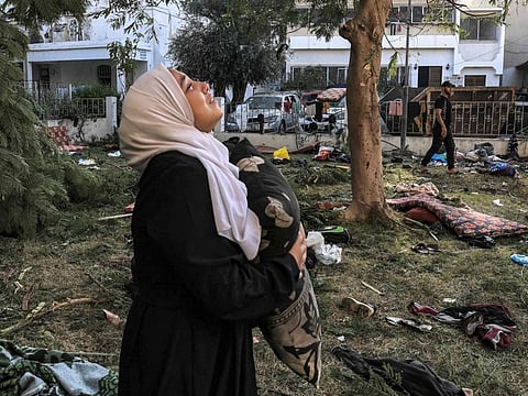 A woman stands amidst debris outside the site of the Al Ahli Al Arab hospital in central Gaza on October 18, 2023 in the aftermath of an overnight strike there.  