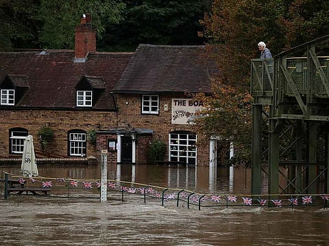 A woman looks out over the flooded beer garden of the Boat Inn after the River Severn burst it's banks near Ironbridge, Britain, October 23, 2023. 