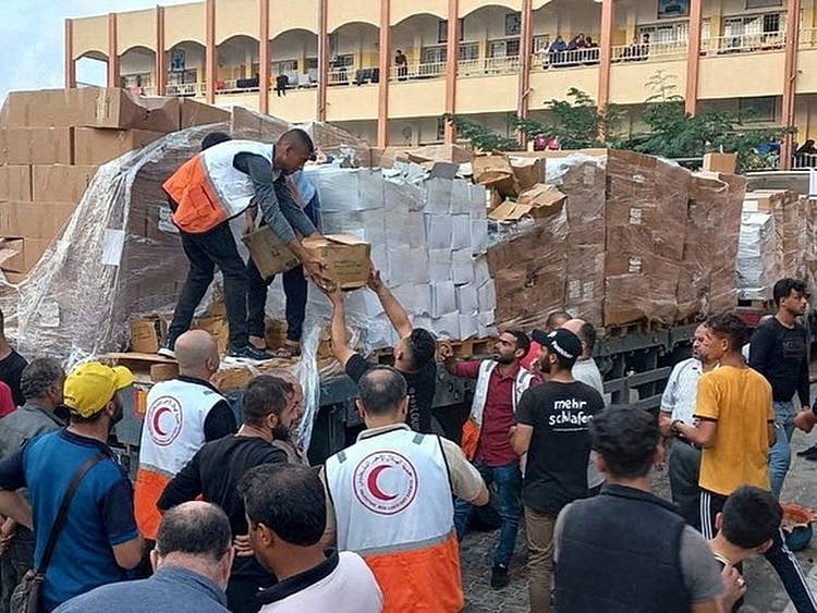 Members of the Palestine Red Crescent Society distribute aid to people in Khan Younis, in the southern Gaza Strip, on October 25, 2023.   