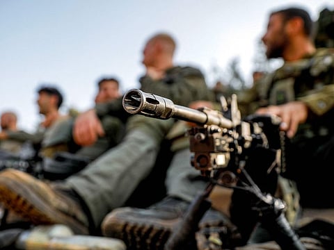 An Israeli army soldier sits by a machine gun deployed on a tripod at a position in the upper Galilee region of northern Israel near the border with Lebanon on October 28, 2023 amid increasing cross-border tensions between Hezbollah and Israel as fighting continues in the south with Hamas militants in the Gaza Strip.  