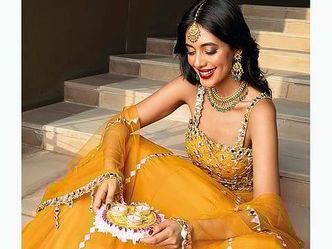 Lehenga set with mirror work by Silky Bindra Dh1,850, VESIMI Props Decor by Diazzz (@diazzz31985) JEWELLERY: Emerald, polki and gold necklace and earrings Dh53,900; Matha patti with rubies and diamonds Dh16,300, all by Devi Jewels