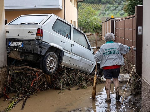 A woman tries to clean the mud in Montemurlo near Prato after heavy rain last night, on November 3, 2023. 