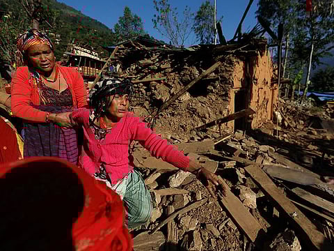 A woman cries as she stands on the rubble of her collapsed house where the members of her family died during an earthquake in Jajarkot, Nepal