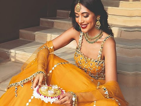 Lehenga set with mirror work by Silky Bindra Dh1,850, VESIMI Props Decor by Diazzz (@diazzz31985) JEWELLERY: Emerald, polki and gold necklace and earrings Dh53,900; Matha patti with rubies and diamonds Dh16,300, all by Devi Jewels